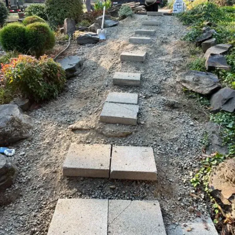 A stone walkway is being built in a garden
