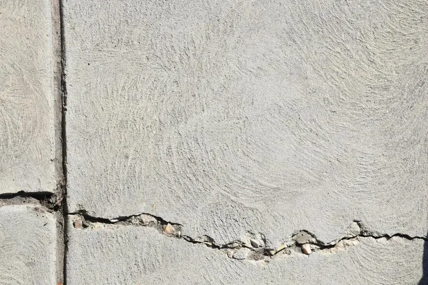 Cracked concrete sidewalk with a visible line between slabs.