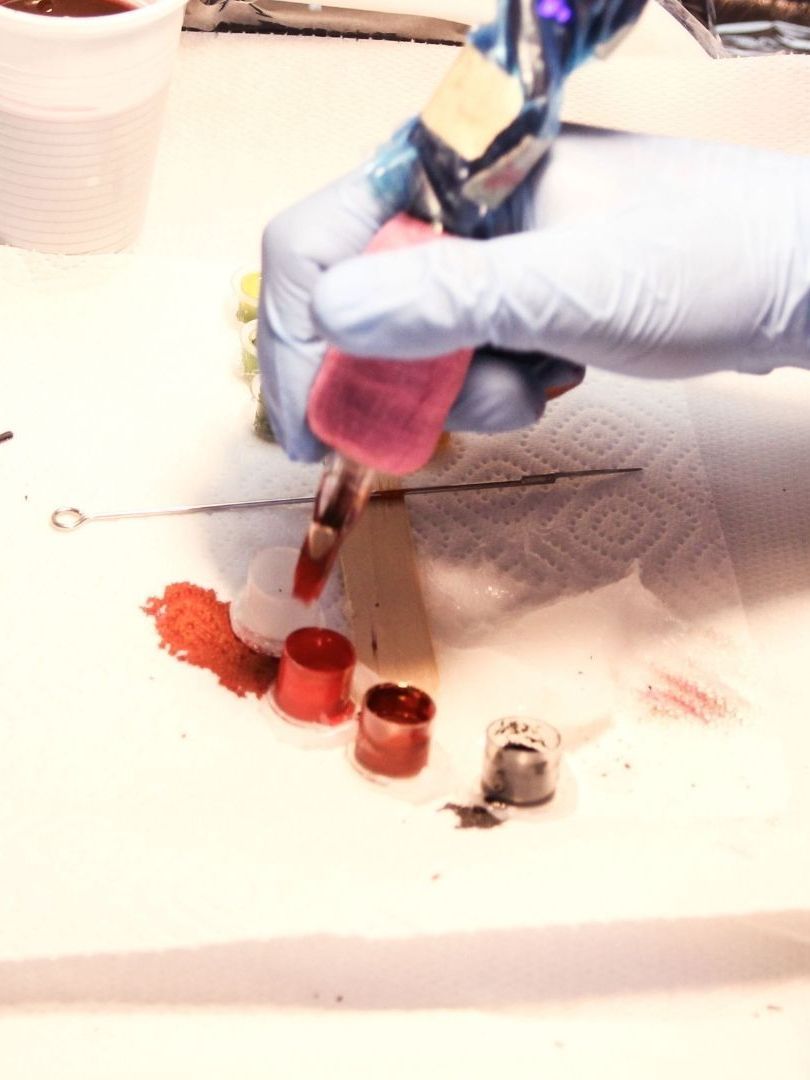 A person wearing blue gloves is holding a pink bottle