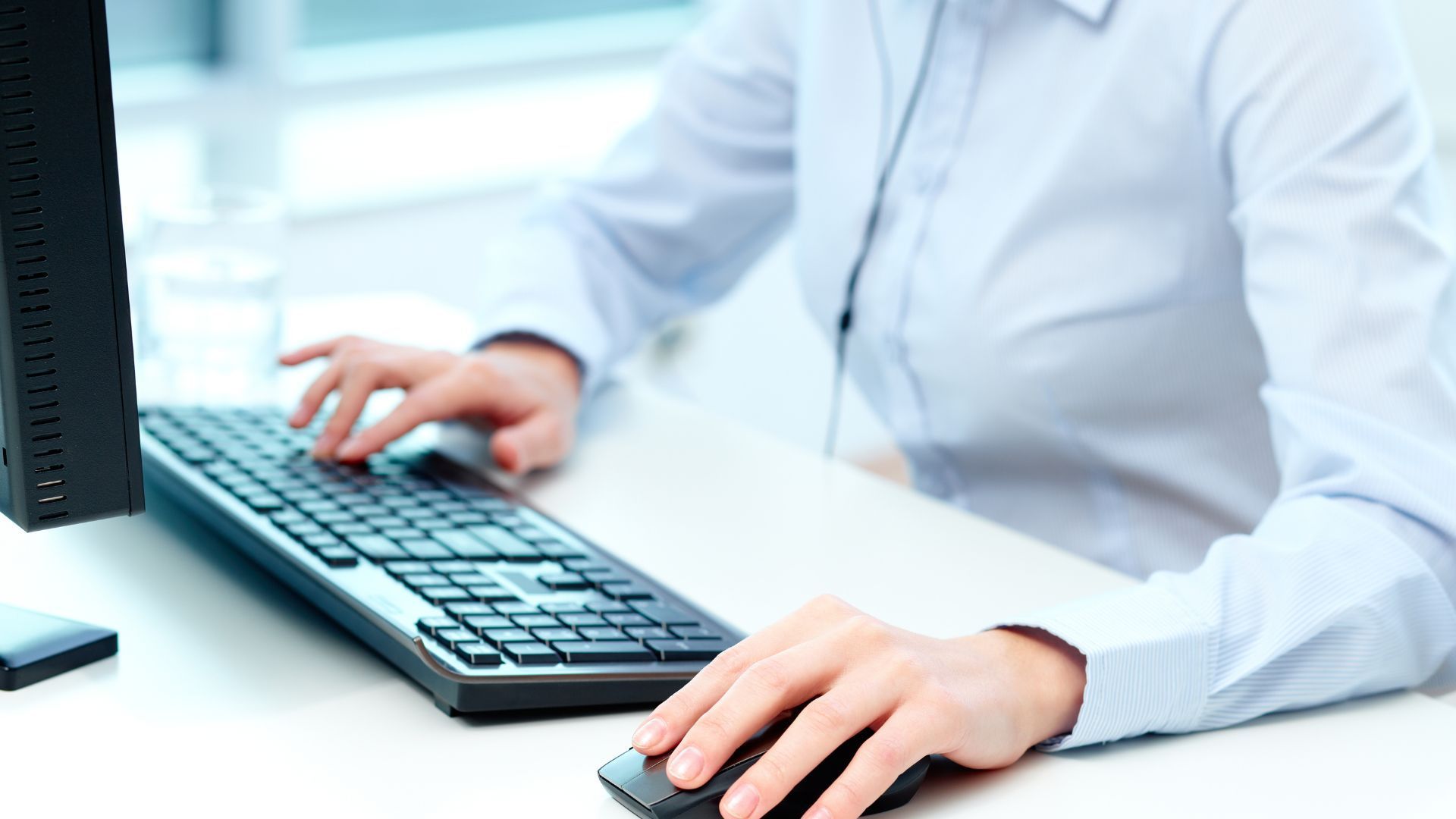 A person is typing on a keyboard and using a mouse