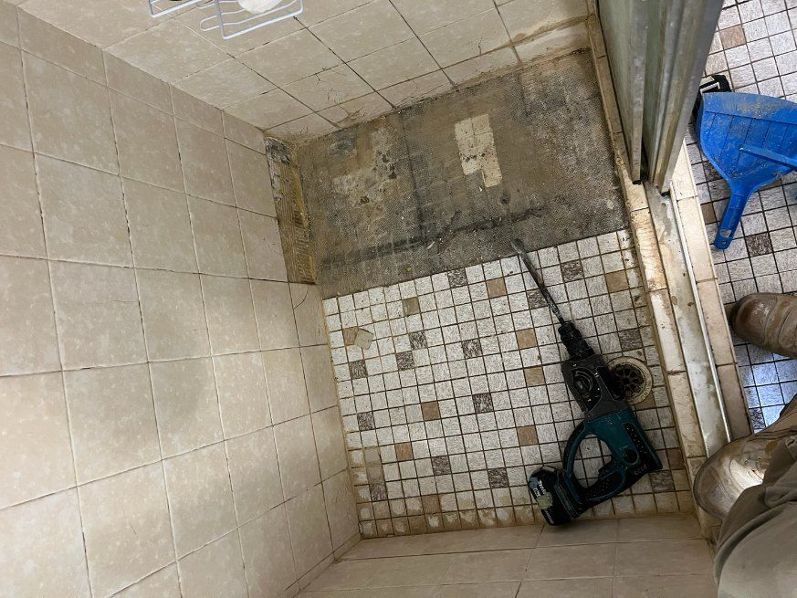 A Drill is Sitting on a Tiled Floor in a Bathroom — Leakproof in Berkeley, NSW