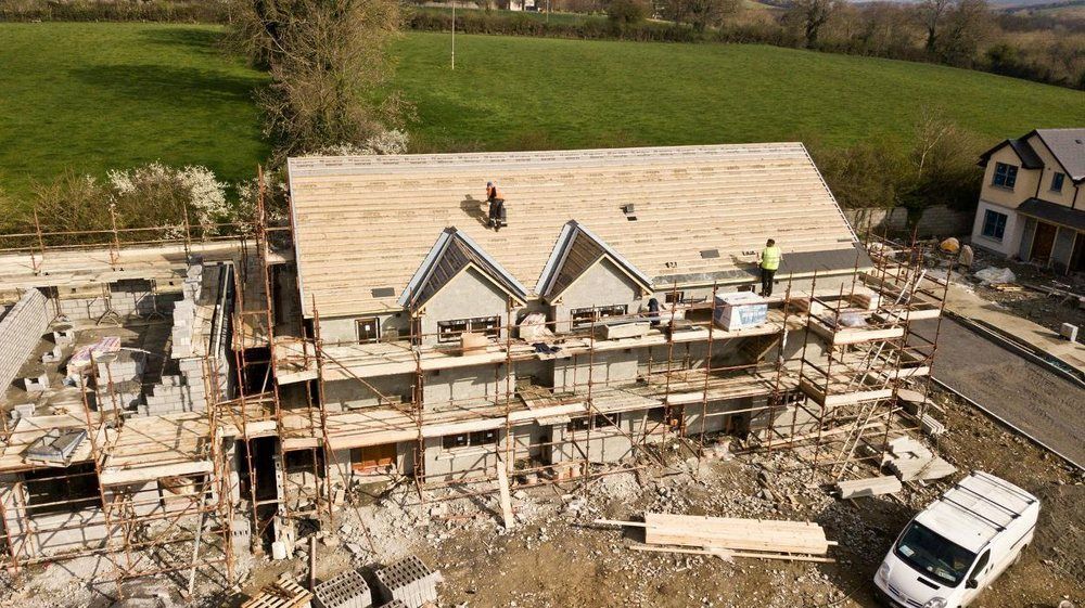 An aerial view of a house under construction with workers on the roof