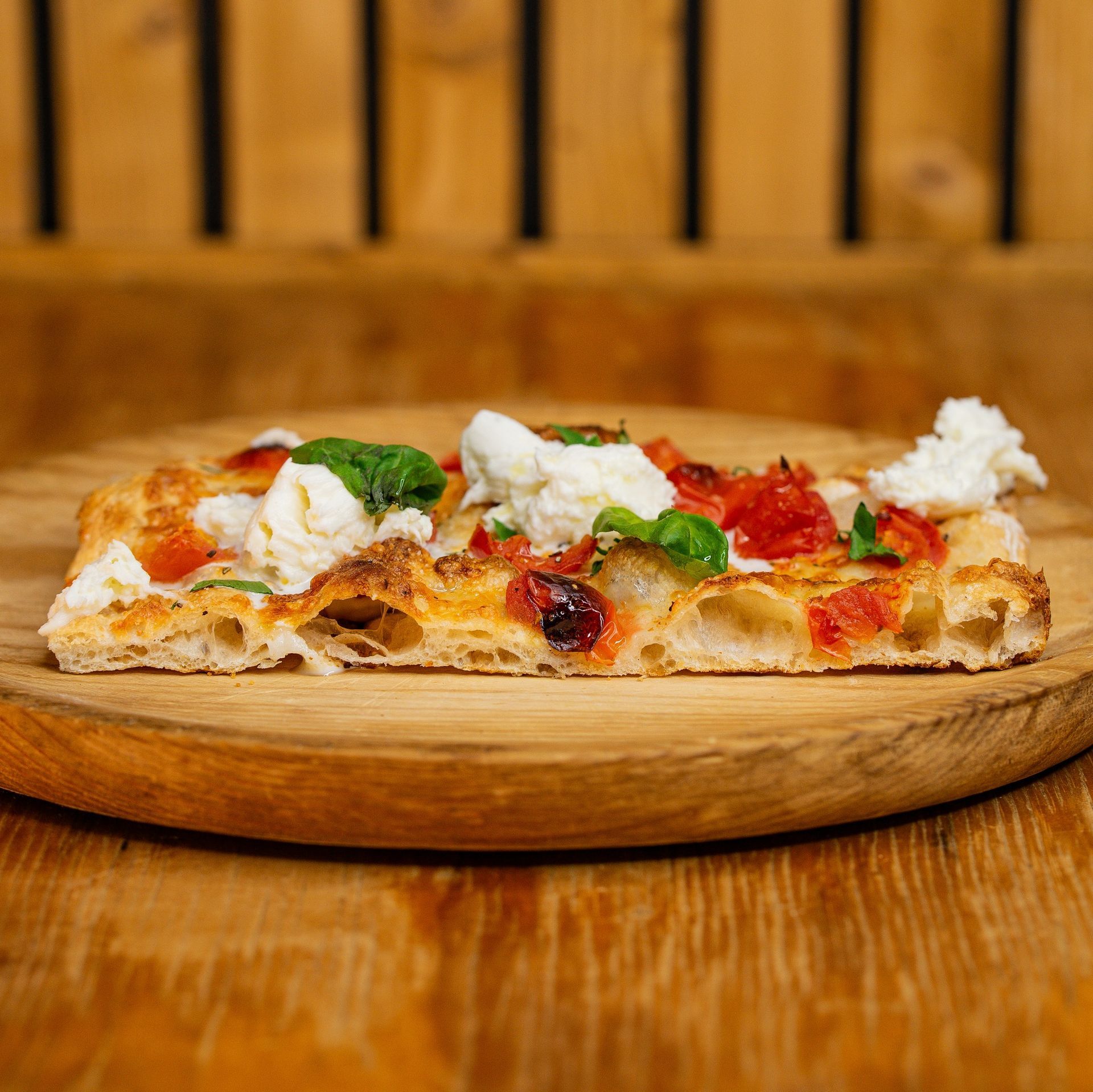 Una fetta di pizza è appoggiata su un tagliere di legno.