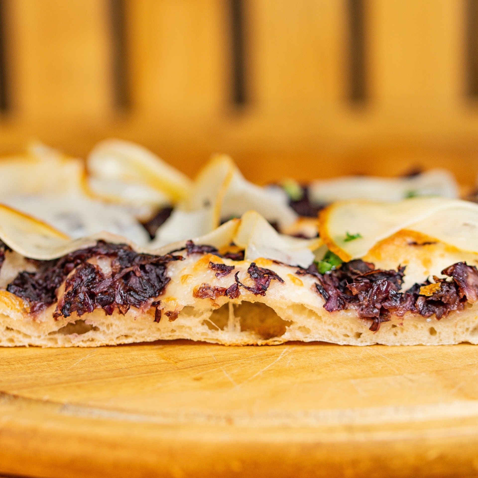Una pizza da cui è stata tolta una fetta si trova su un tagliere di legno.
