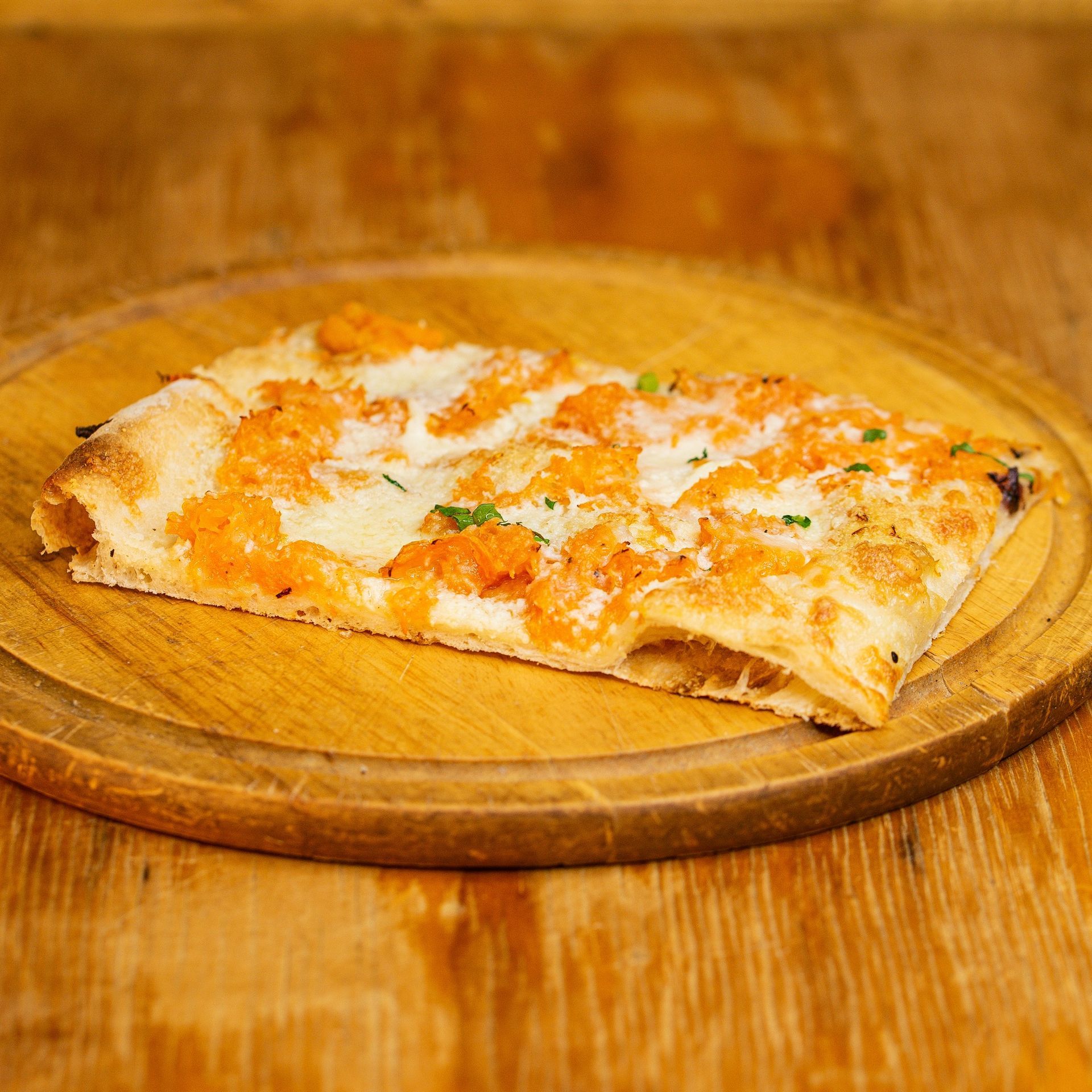 Una fetta di pizza è appoggiata su un tagliere di legno su un tavolo di legno.