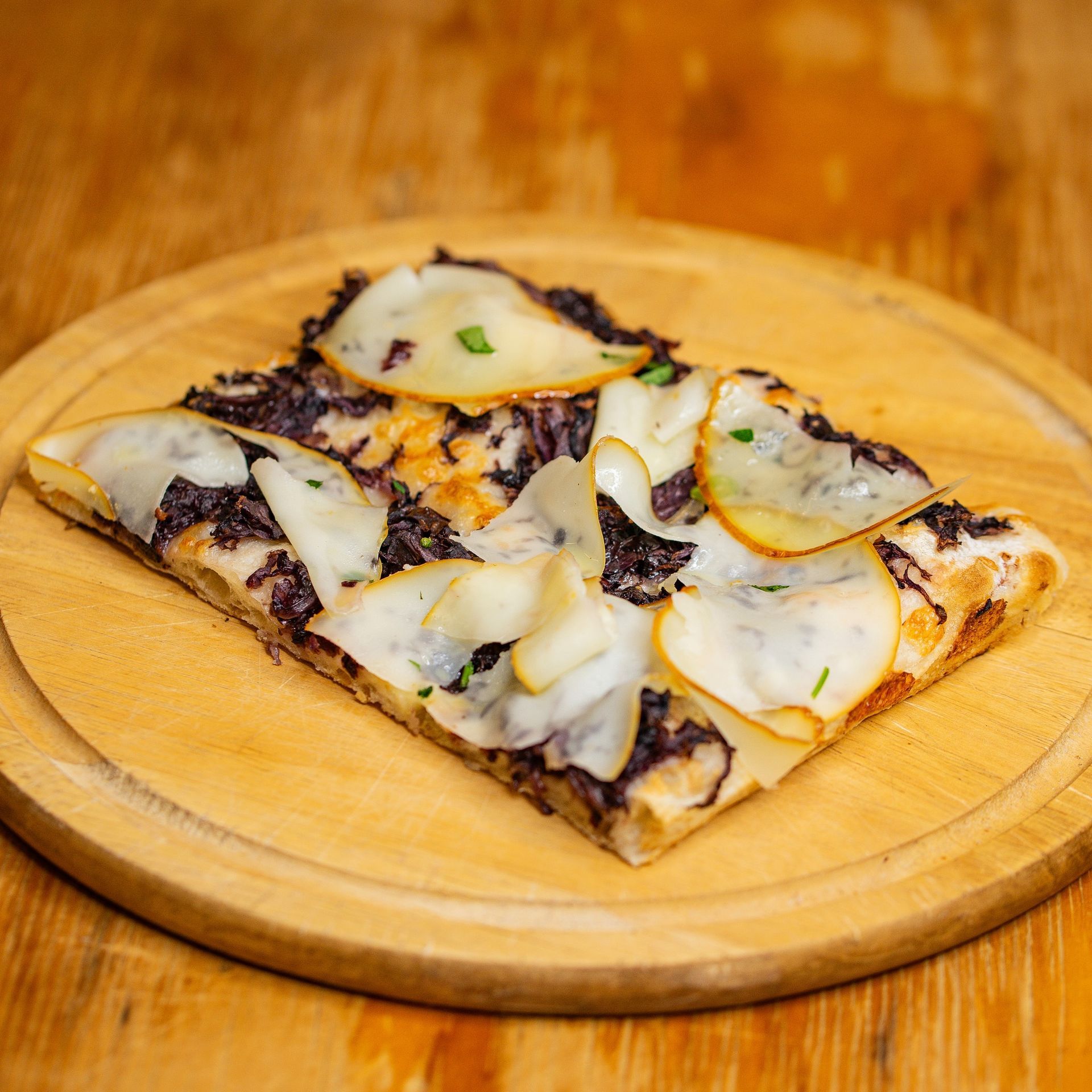 Una fetta di pizza su un tagliere di legno su un tavolo di legno.