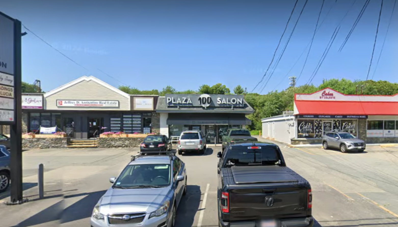A lot of cars are parked in a parking lot in front of a building.
