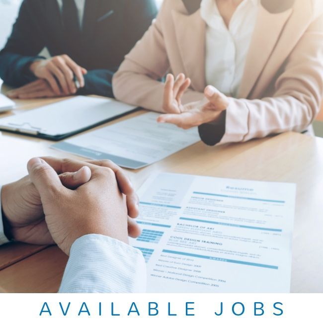 Business professionals sitting at a table with resumes, discussing available jobs.