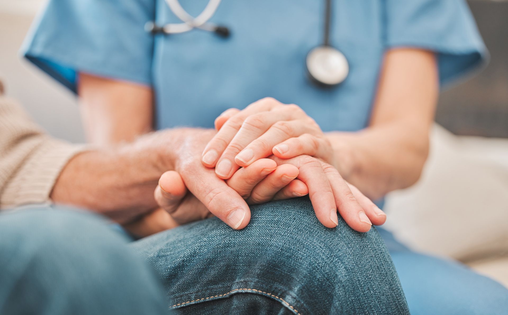 A caregiver is holding the hand of a patient.
