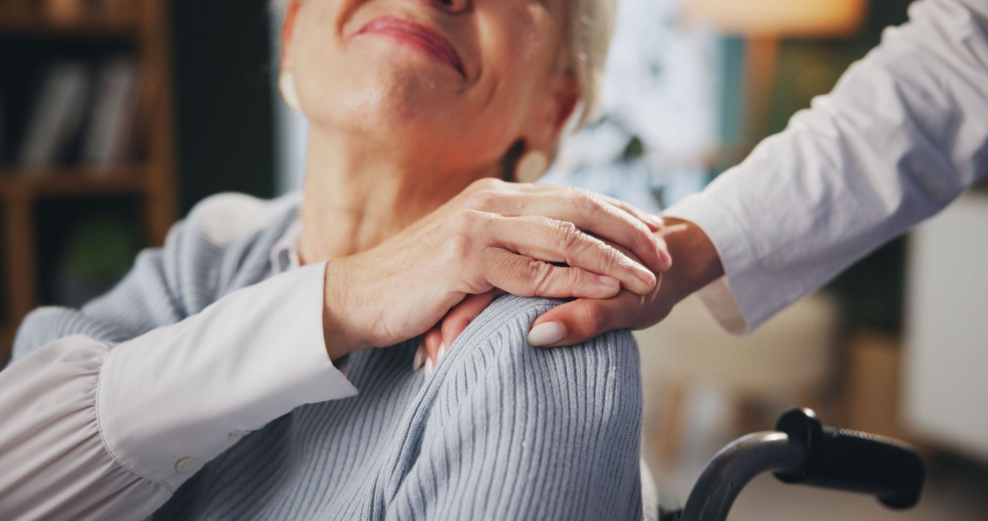 An elderly woman in a wheelchair is being comforted by a caregiver.
