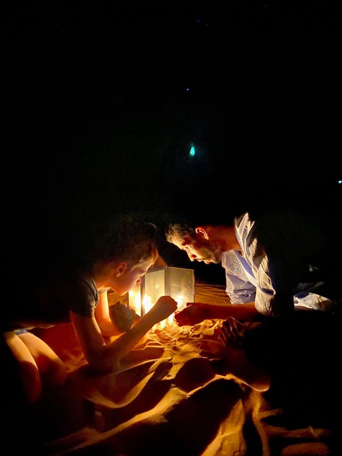 Travelers huddled around a campfire under the starry desert sky.