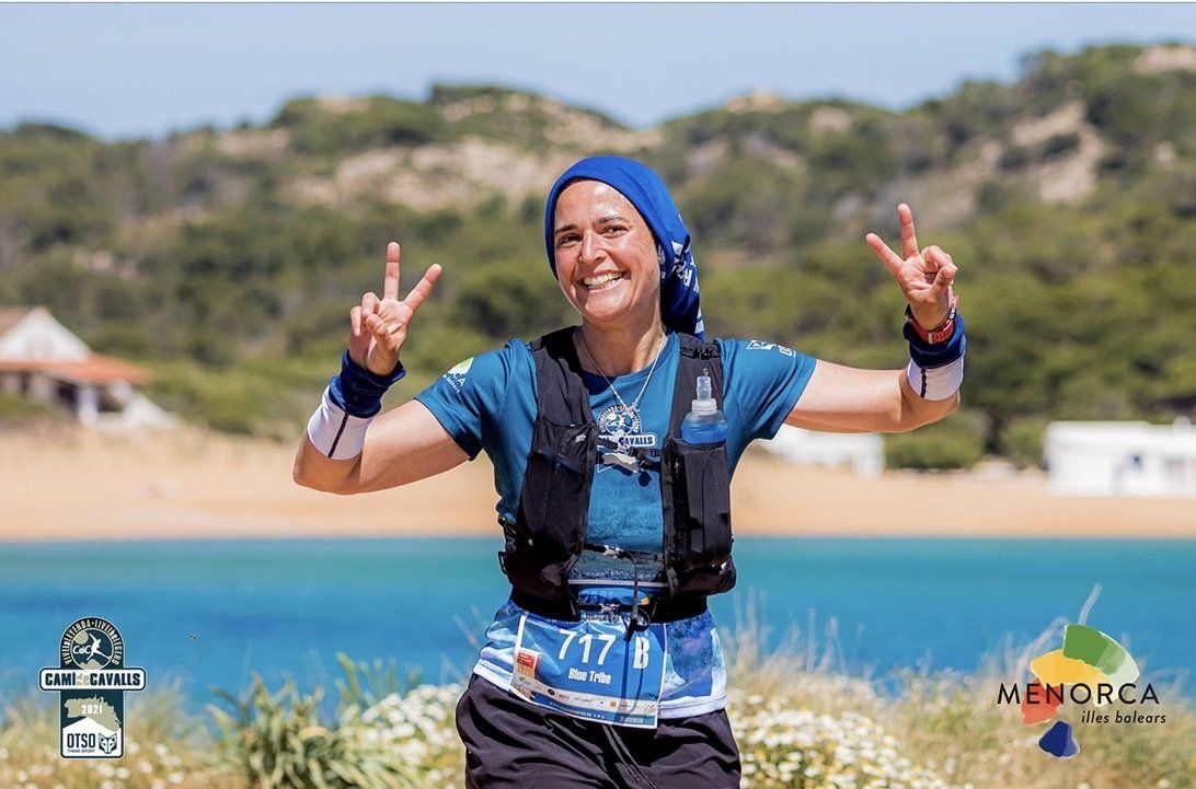 Una mujer está haciendo un signo de paz frente a un cuerpo de agua.