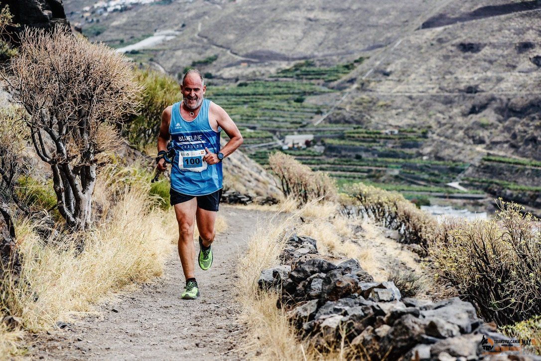 Un hombre corre por un camino de tierra en las montañas.