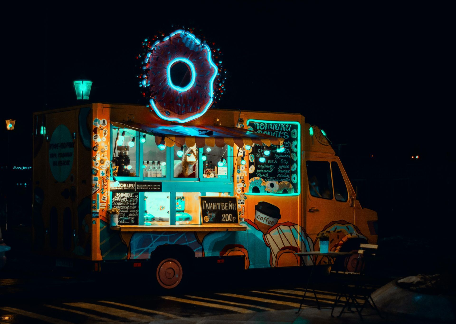 A food truck with a donut on top of it at night.
