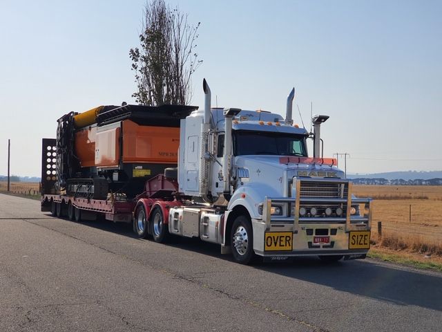 A white semi truck with a yellow over sign on the side of it
