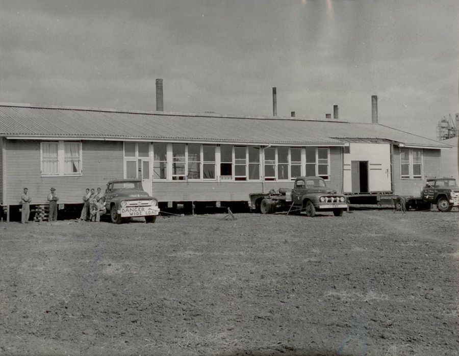 A black and white photo of a house with cars parked in front of it