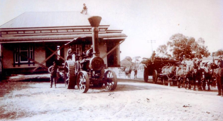 A black and white photo of a tractor in front of a building