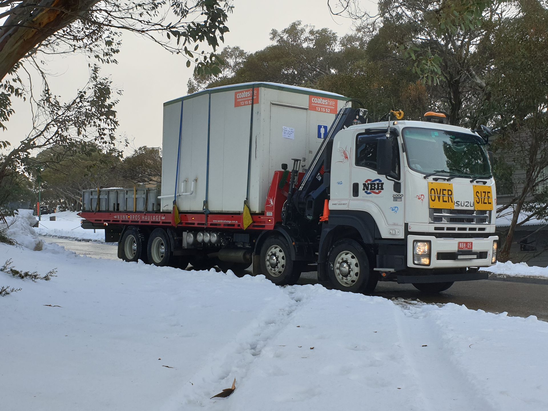A white truck is driving down a snowy road.