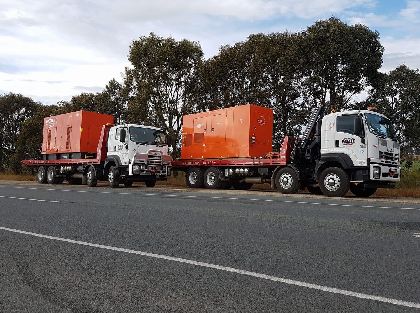 Three trucks are parked on the side of the road.