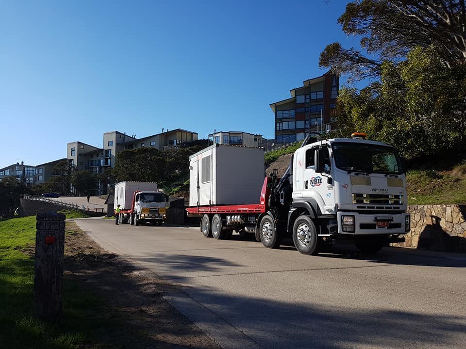 A white truck is driving down a road with a red flatbed trailer.