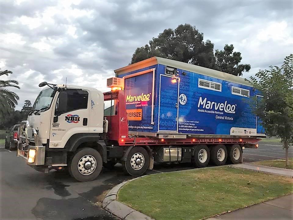A blue and white marvellog truck is parked on the side of the road.