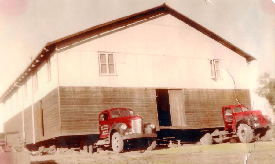 Two red trucks are parked in front of a white building