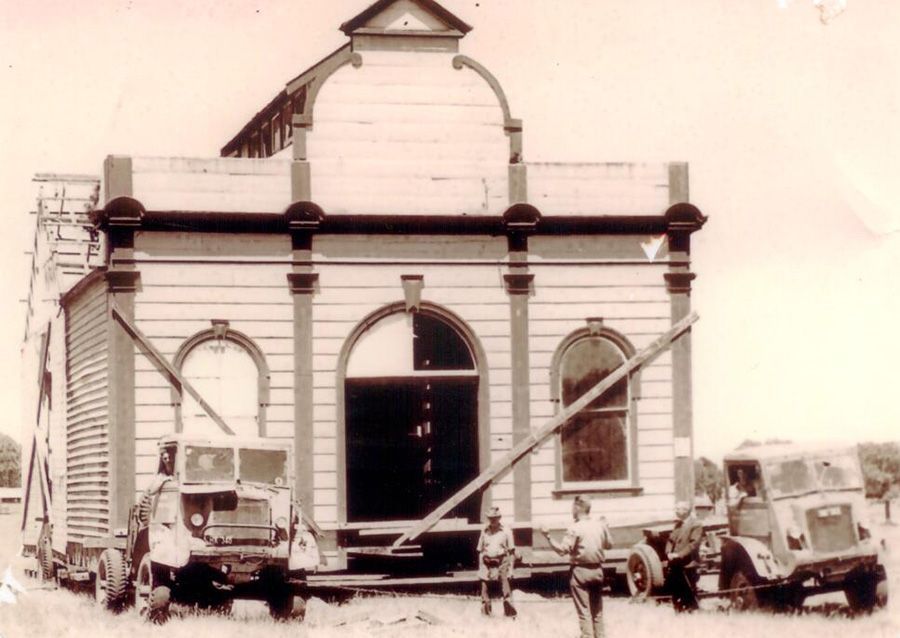 A black and white photo of a building being moved