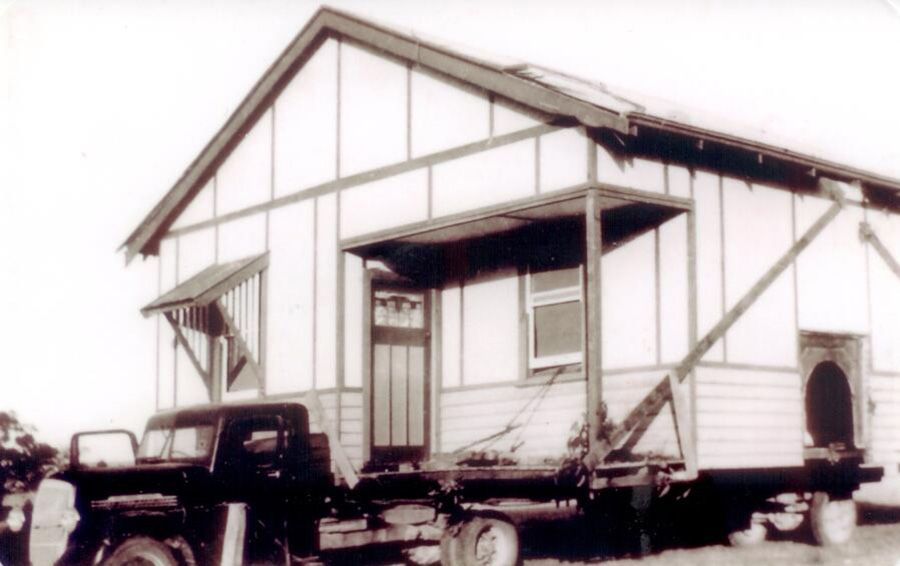 A black and white photo of a truck parked in front of a house