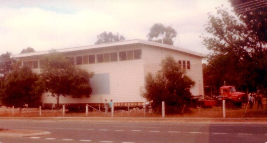 A large white building with a red truck parked in front of it.