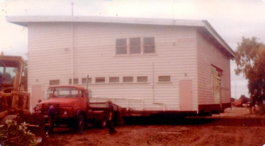 A red truck is parked in front of a white house.