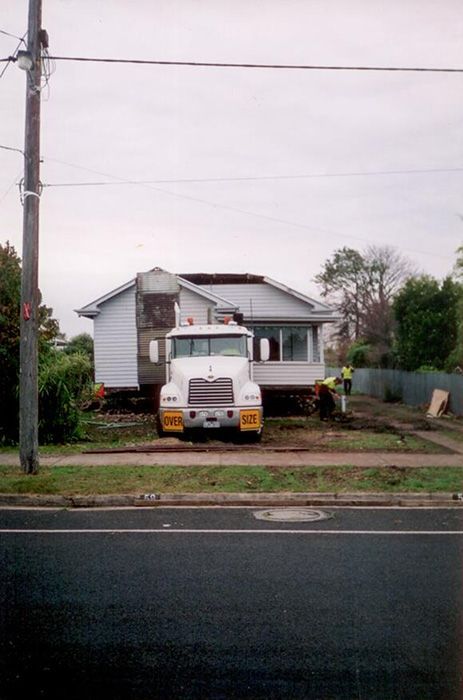 A white truck is parked in front of a house that is being moved
