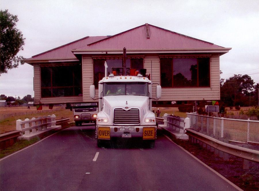 A mack truck is driving down a road next to a house