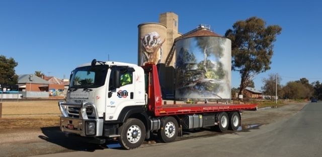 A tow truck is parked on the side of the road next to a silo.