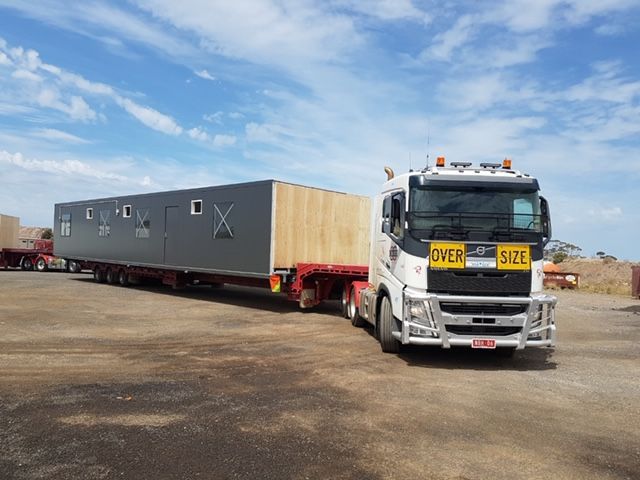 A large truck is carrying a large box on a trailer.