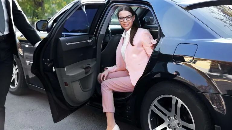White Ford Transit van parked outside a store on a sunny day. A black pickup truck is in the background.