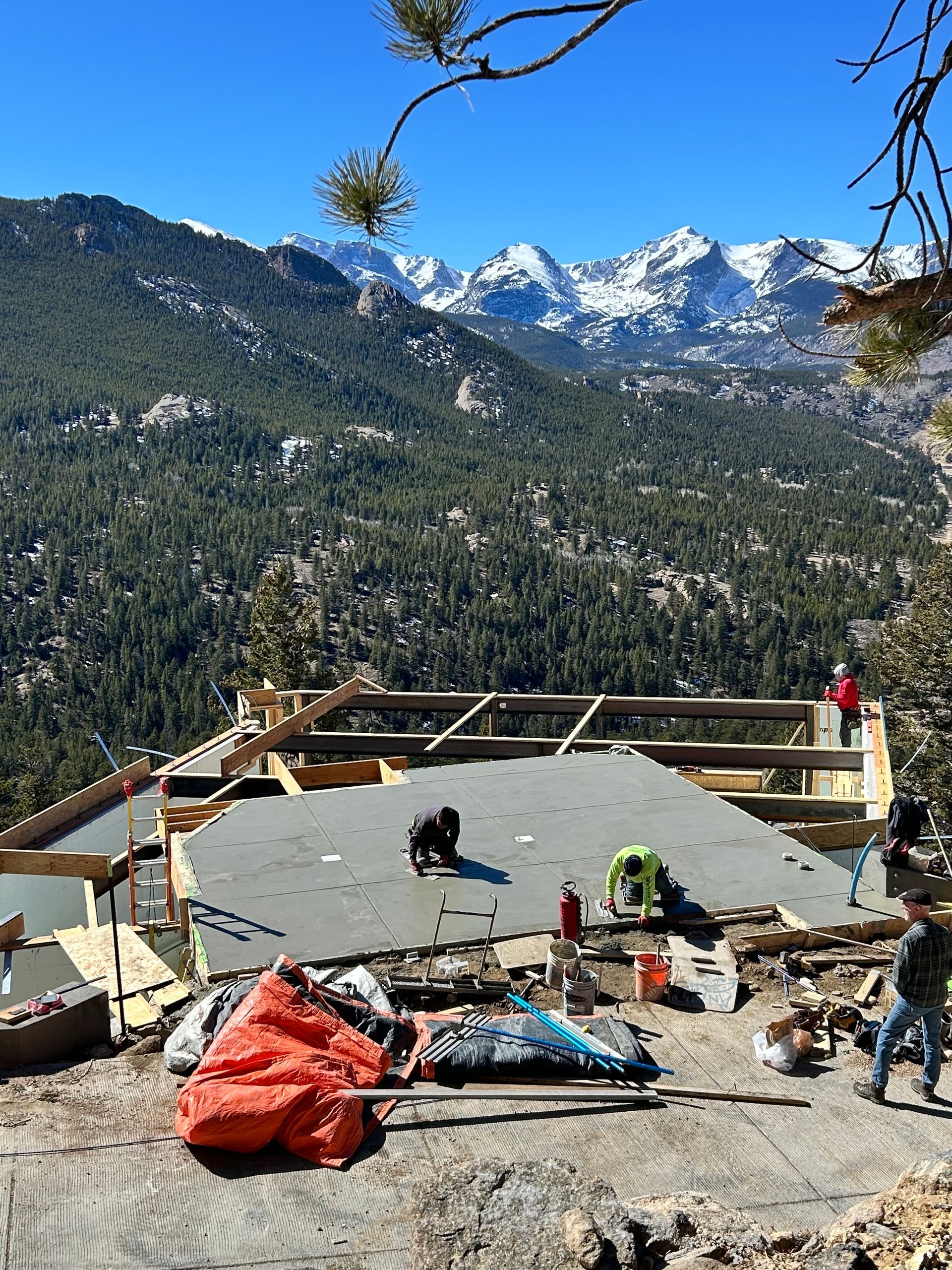 Construction crew working on a roof with a mountain backdrop.