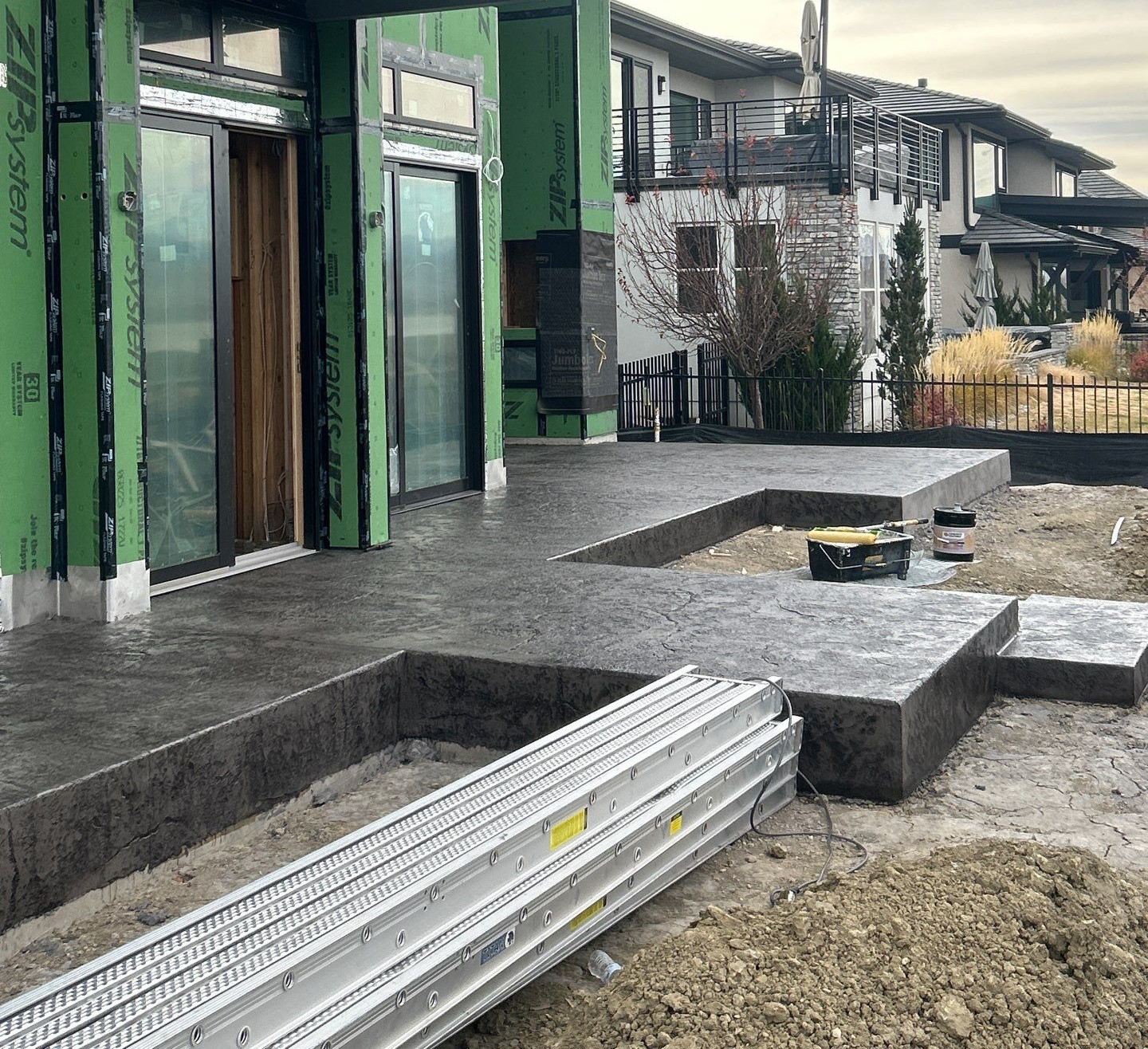 Exterior view of a house under construction with a concrete patio.