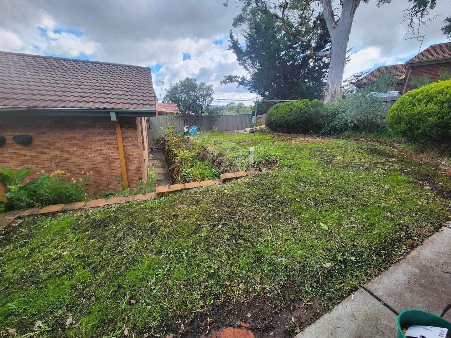 Before A Lush Green Yard With A Brick House In The Background — Canberra Home and Garden Maintenance in Tuggeranong ACT