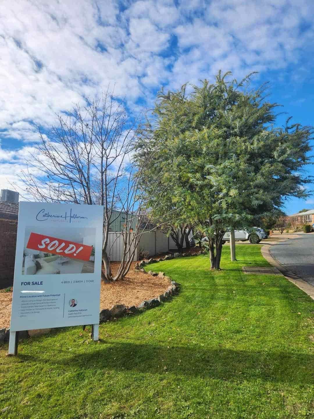 A Sold Sign is Sitting in the Grass Next to a Tree — Canberra Home and Garden Maintenance in Gordon, ACT