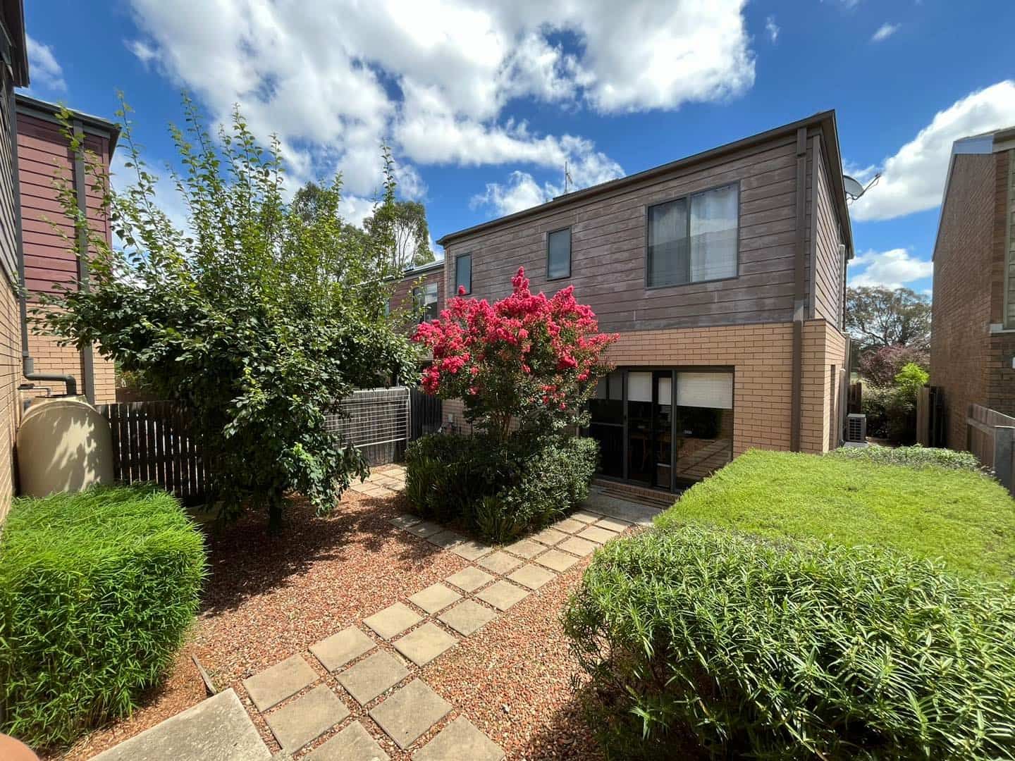 A brick house with a lush green garden in front of it — Canberra Home and Garden Maintenance in Gordon, ACT.