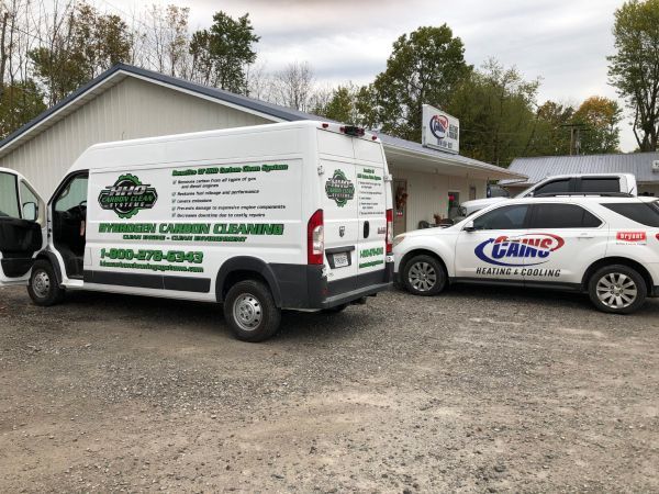 A white van and a white car are parked in front of a building | HHO Carbon Clean Systems - North Atlanta