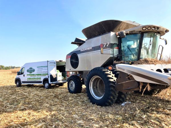 A combine harvester is sitting in a field next to a van |  HHO Carbon Clean Systems - North Atlanta