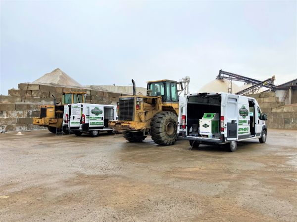 Three vans are parked next to a bulldozer in a parking lot | HHO Carbon Clean Systems - North Atlanta