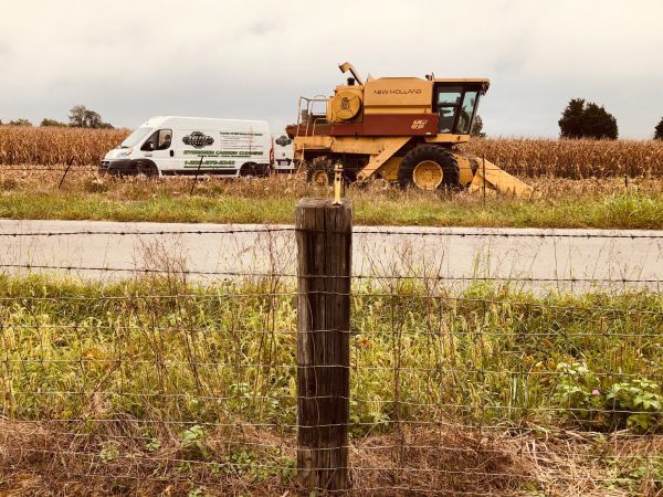 A yellow combine harvester is in a field next to a white van | HHO Carbon Clean Systems - North Atlanta