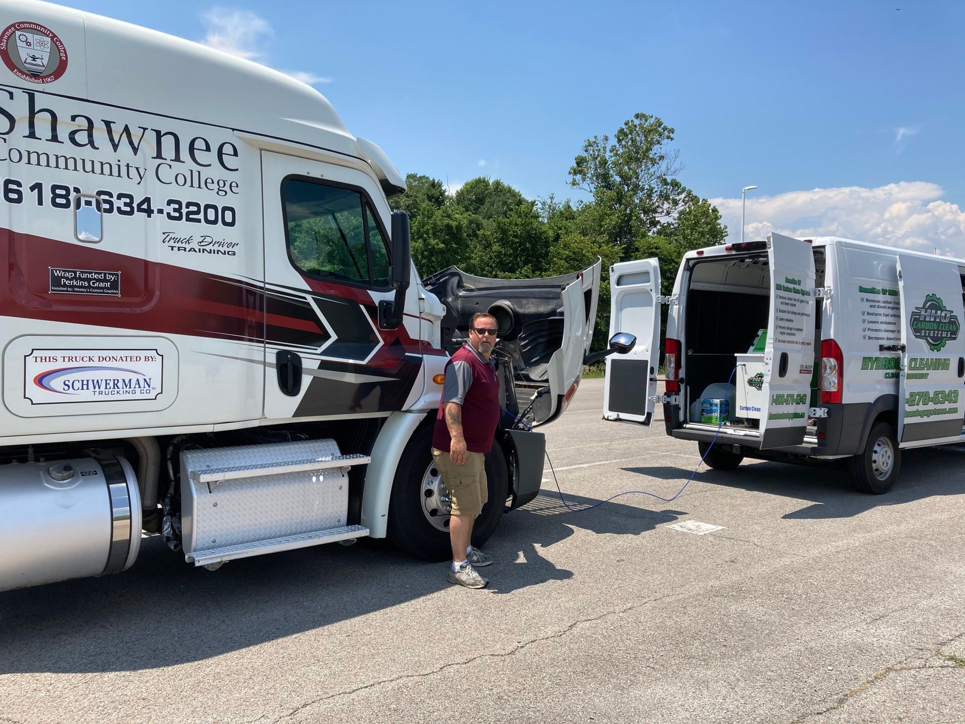 A man is standing next to a semi truck and a van | HHO Carbon Clean Systems - North Atlanta