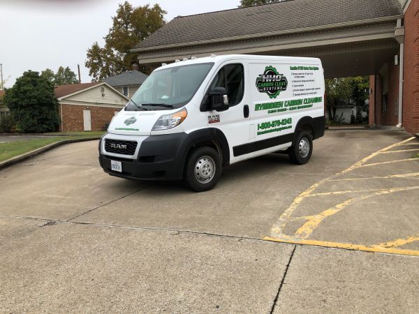 A white van is parked in a parking lot in front of a building | HHO Carbon Clean Systems - North Atlanta