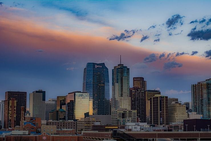 A city skyline at sunset with a cloudy sky in the background.