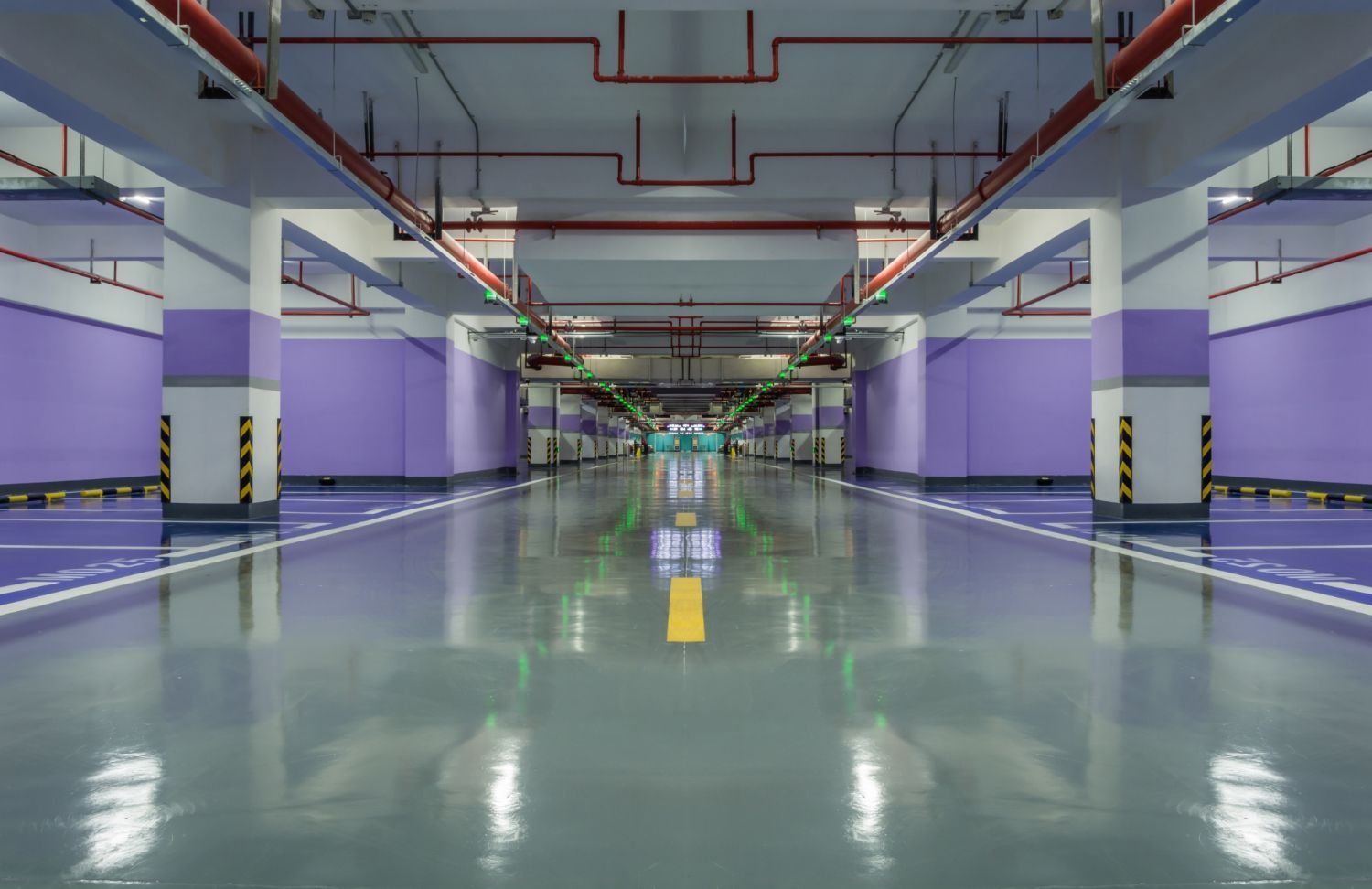 Green, rusty metal support on a concrete block wall, holding a horizontal pipe.