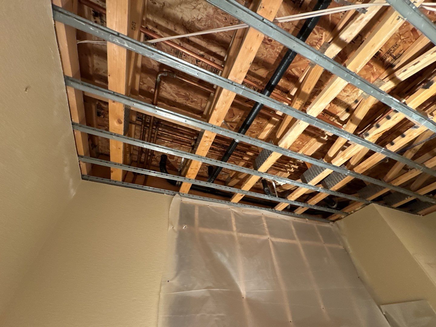 A room with a wooden ceiling and a plastic sheet on the wall.