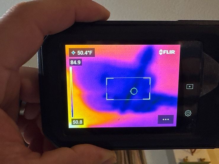 A person is holding a phone with a thermal camera on it